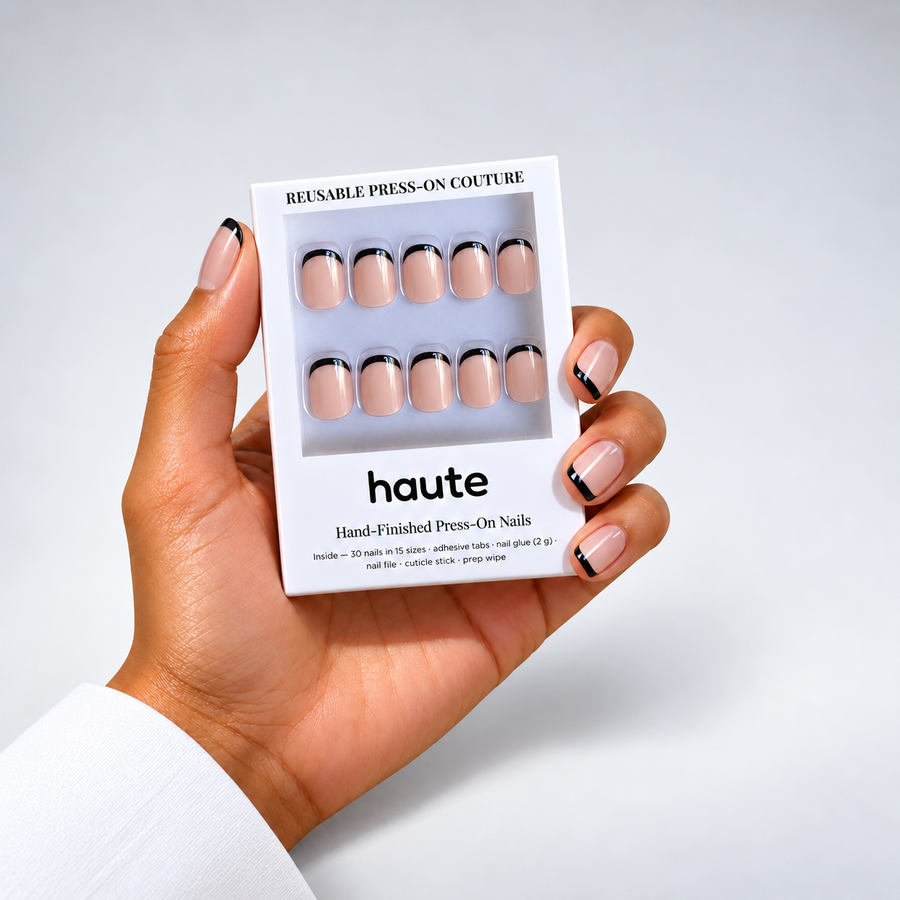 hand wearing black tie press-on nails holding the haute box